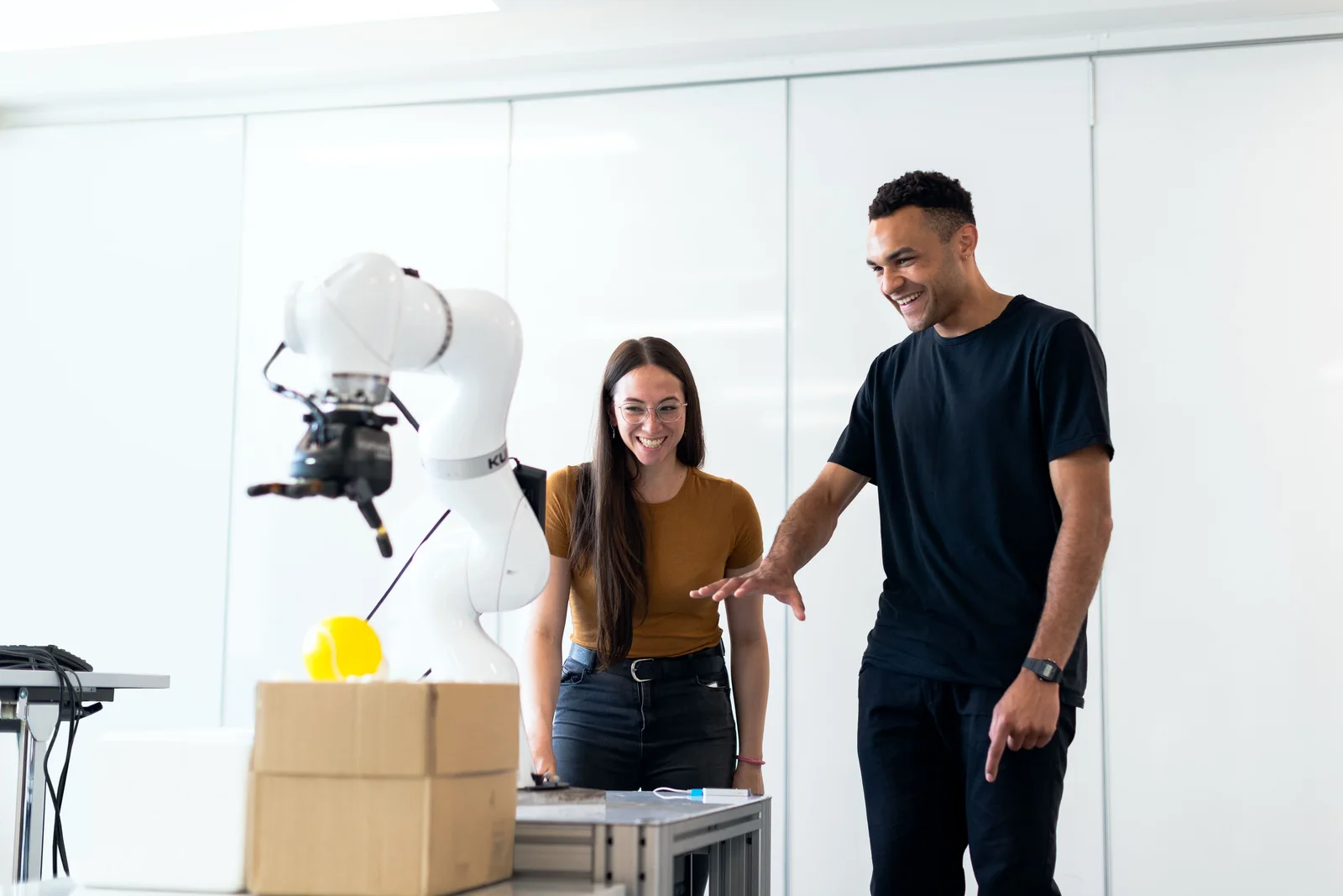 Two engineers testing a white humanoid robot in a workshop